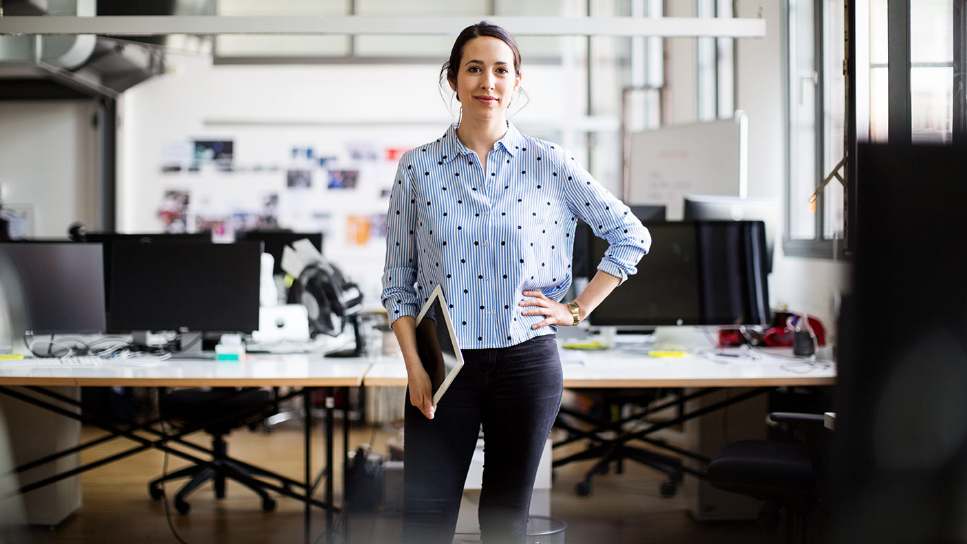 Portrait of confident female entrepreneur standing with hand on hip while holding digital tablet at creative office