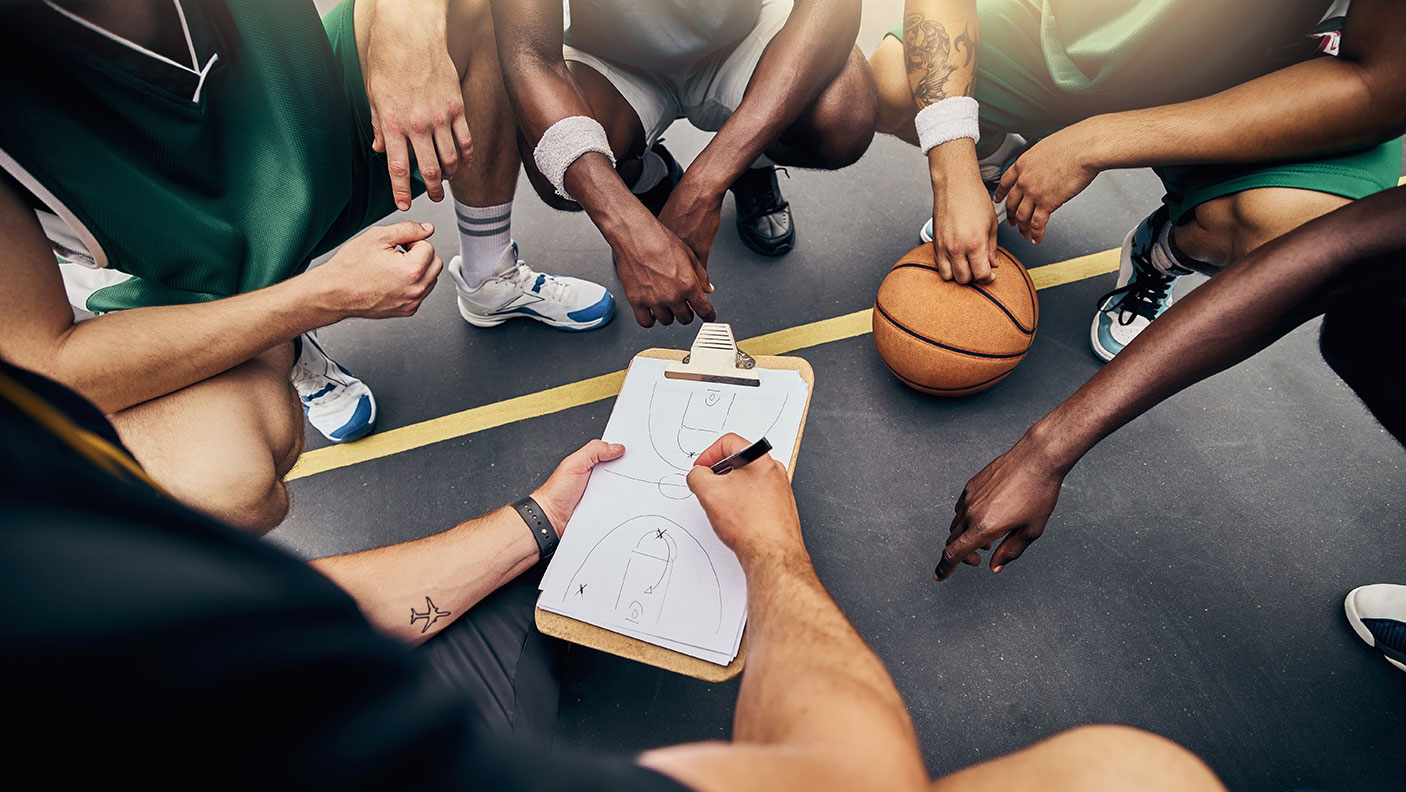 Basketball team members crowd around the coach discussing the gameplan.